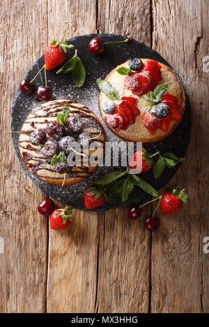 Gâteaux délicat avec du chocolat, menthe et fraises, cerises et bleuets close-up sur la table. Haut Vertical Vue de dessus Banque D'Images