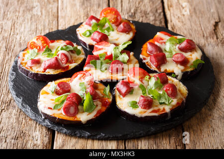 Collation de petites aubergines avec du fromage, des tomates, des saucisses et de la sauce gros plan sur une ardoise sur la table. L'horizontale Banque D'Images