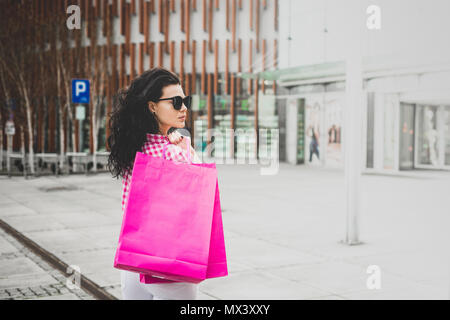 La femme est de retour de shopping. A girl wearing jeans blanc et une chemise à carreaux est holding shopping bags dans ses mains. Banque D'Images