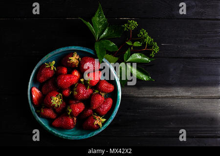 Photo : Contraste des fraises dans une assiette verte sur un tableau noir Banque D'Images