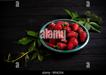 Photo : Contraste des fraises dans une assiette verte sur un tableau noir Banque D'Images