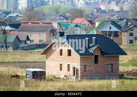 Toute nouvelle brique spacieuse maison d'habitation de deux étages avec toit et fenêtres carrelage ouvertures dans quartier de banlieue sur fond de ville lointaine.Buil Banque D'Images