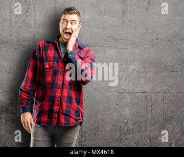 Jeune homme séduisant si heureux et confiant montrant un grand sourire surpris collés Banque D'Images