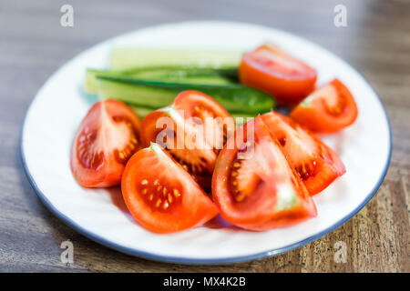 Gros plan macro de tranches de tomates mûres et juteuses tranches de concombres sur la plaque, table en bois comme collation santé ou salade apéritif Banque D'Images