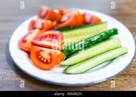 Tranches de tomates mûres et juteuses tranches de concombres sur la plaque gros plan macro, table en bois comme collation santé ou salade apéritif Banque D'Images