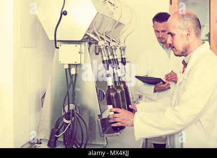 Portrait of mature européenne homme winery travailleur avec des machines d'embouteillage sur factory Banque D'Images