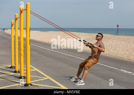 Un homme photographié en utilisant l'équipement d'exercice en plein air sur la plage de Littlehampton, West Sussex, UK. Banque D'Images