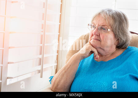 Senior Woman Gazing contemplative hors de sa fenêtre. Banque D'Images