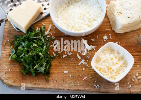 La Frittata ingrédients : oeufs battus et le lait, et l'halloumi fromage parmesan, basilic coupé Banque D'Images