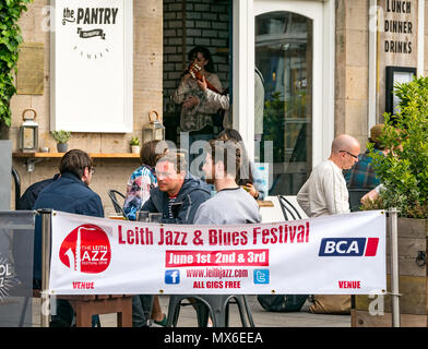 Leith Jazz & Blues Festival de musique live dans les restaurants et bars par l'eau de Leith, 3e juin 2018. La Rive, Leith, Edinburgh, Ecosse, Royaume-Uni. Le Jazz and Blues Festival se déroule sur 3 jours de semaine. Les gens envahissent la chaussée extérieure tables des restaurants et bars au bord de l'eau de Leith bénéficiant d'écouter de la musique en direct gratuit. Des gens assis à des tables à l'extérieur d'un bar appelé le garde-manger avec le festival affiche bannière Banque D'Images