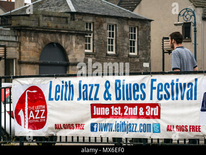 Leith Jazz & Blues Festival de musique live dans les restaurants et bars par l'eau de Leith, 3e juin 2018. La Rive, Leith, Edinburgh, Ecosse, Royaume-Uni. Le Jazz and Blues Festival se déroule sur 3 jours de semaine. Le festival affiche bannière sur un pont au-dessus de l'eau d'un Leith avec un homme en passant devant une ancienne lampe ornés poster Banque D'Images