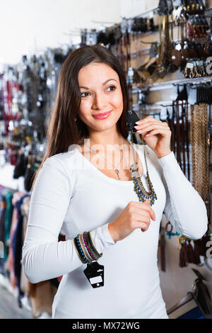 Cheerful young happy smiling woman en choisissant différents pendentifs et bracelets sur le marché Banque D'Images