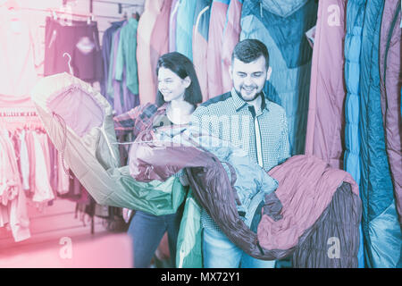 Smiling couple l'examen de divers sacs de couchage au magasin d'équipement de sport Banque D'Images