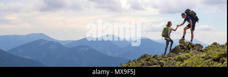 Les jeunes touristes avec des sacs à dos, athlétique garçon fille slim permet à l'ICLÉM rocky mountain top impression contre ciel d'été et l'arrière-plan de montagnes. Touri Banque D'Images