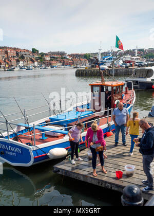 Une famille de vacanciers soleil du printemps sur un bateau de pêche au crabe, à l'atterrissage à New Quay à Whitby Harbour Banque D'Images