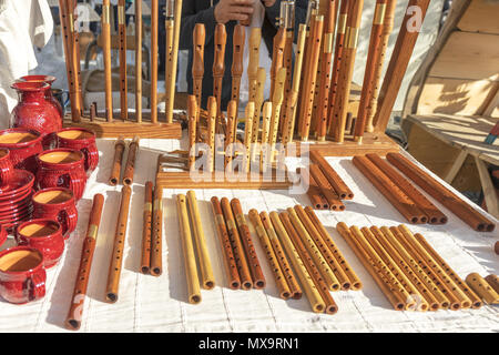 Tasses en céramique et de casseroles, sifflets en bois, instruments de musique en bois, de la rue du marché, des biens affichés sur la table. Banque D'Images