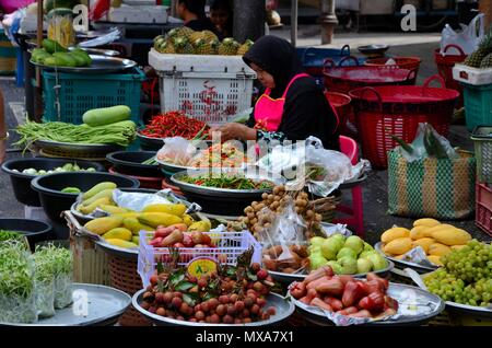 Dame en noir tudung hijab vend des fruits et légumes au marché de rue bazar Hatyai Thaïlande Banque D'Images