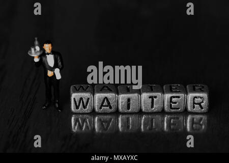 Serveur sur billes avec un modèle à l'échelle waiter standing next to word sur fond de bois Banque D'Images
