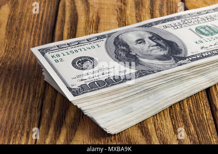 Une pile de one hundred dollar American notes jetées sur une table en bois. Banque D'Images