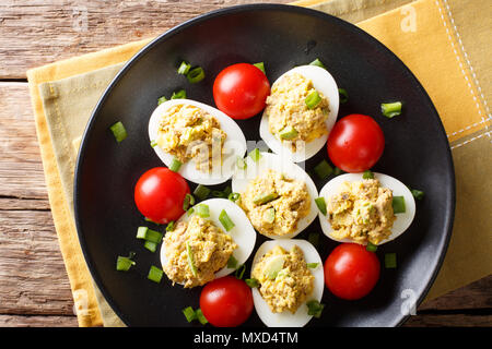 Oeufs farcis cuits avec du thon et d'avocat avec tomates et oignons verts close-up sur une plaque sur une table. Haut horizontale Vue de dessus Banque D'Images