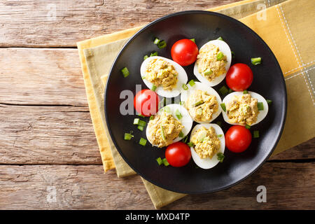 Oeufs farcis farcis au thon et d'avocat servi avec tomates et oignons verts gros plan sur une assiette. Haut horizontale Vue de dessus Banque D'Images