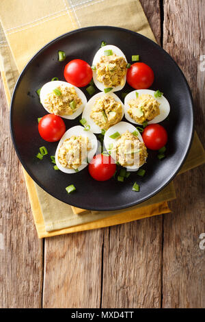 Oeufs farcis farcis au thon et d'avocat servi avec tomates et oignons verts gros plan sur une assiette. Haut Vertical Vue de dessus Banque D'Images