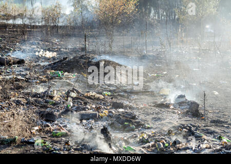 La combustion des déchets illicites de déchets à dumo près de la forêt. Terre noire et lourde fumée indésirable. Conséquences de la pollution de l'environnement concept. Banque D'Images