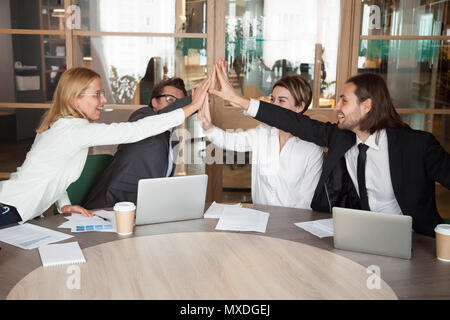 Heureux de l'équipe de travail, offrant un rapport commun pour célébrer cinq achievemen Banque D'Images