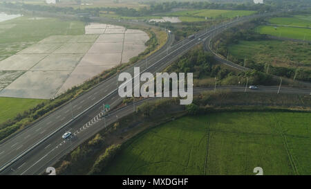 Vue aérienne avec des voitures de la route entre les champs des agriculteurs, des terrasses de riz. Aux Philippines, l'île de Luçon. Highwayin à grande vitesse le Morning Sunrise.paysage tropical en Asie. Banque D'Images