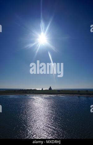 Un soleil en forme d'arrondi au-dessus de la silhouette du phare de Wood Islands (1876) sur la rive sud-est de l'Île du Prince Édouard, Canada. Banque D'Images