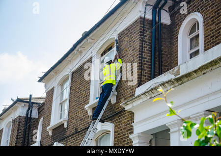 Un ingénieur Openreach sur une échelle travaillant sur une ligne téléphonique Connexion à une propriété résidentielle. Banque D'Images