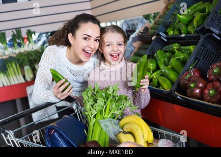 Heureux et joyeux des femmes positives smiling little girl shopping verts dans les épiceries Banque D'Images