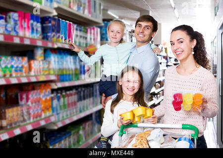 Smiling parents avec deux enfants l'achat de yogourt aux fruits et au lait Banque D'Images