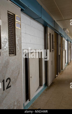 Rangée de métal numérotée portes déverrouillées cellulaire le long couloir abandonné à l'intérieur de la prison. Banque D'Images