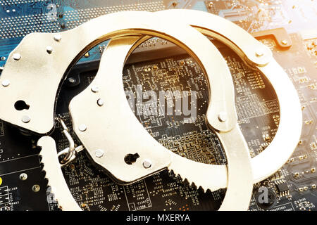 Les menottes et les appareils électroniques. La cybercriminalité ou la fraude. Banque D'Images