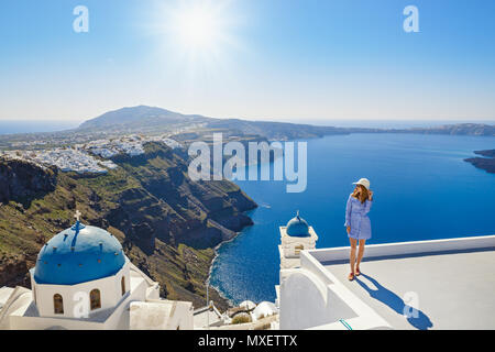 Jeune femme se dresse sur une colline et regarde le paysage marin de Santorini, Grèce Banque D'Images