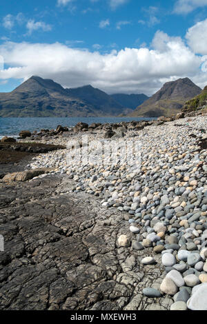 Galets et rochers de Glen Scaladal Bay (Cladach un Ghlinne) près d'Elgol, avec vue sur la mer et montagnes Cuillin noires au-delà, l'île de Skye, Écosse, Royaume-Uni Banque D'Images