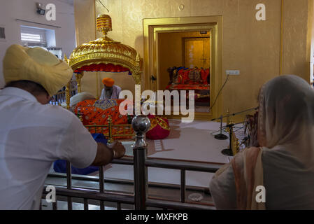 Une femme dans un sari et un homme dans un turban prient dans un temple sikh. Inde Delhi Temple d'or juin 2015 Banque D'Images