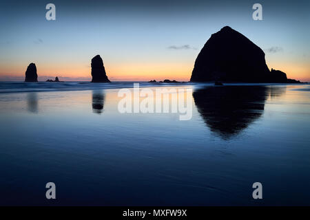 Haystack Rock Sunset, Cannon Beach, Oregon Sunset at Haystack Rock de Cannon Beach, Oregon dans le surf comme échoués sur la plage. United States. Banque D'Images