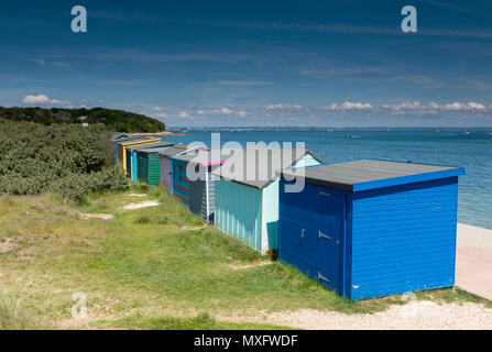 Une rangée de cabines colorées sur la côte à St Helens duver près de bembridge, sur l'île de Wight sur une chaude journée d'été ensoleillée et ciel bleu avec des nuages. Banque D'Images