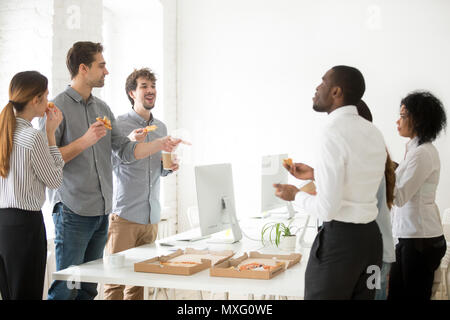 L'équipe diversifiée Positive Eating pizza et discuter sur le lieu de travail Banque D'Images