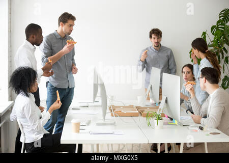 Groupe de travail multinational de parler et de manger des pizzas sur le lieu de travail Banque D'Images