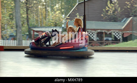 Mère heureuse avec sa fille en voiture sur auto-tamponneuses dans Amusement Park Banque D'Images