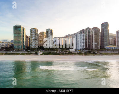 Paysage photo aérienne de la plage Barra da Tijuca , avec des vagues se brisant sur la plage au lever du soleil, avec le front de bâtiments dans l'arrière-plan Banque D'Images