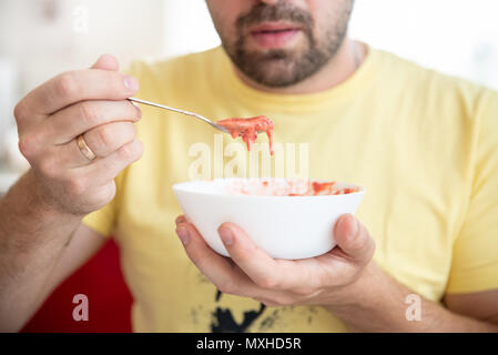 L'homme goûte des yaourts faits maison à base de fraises et de crème sure, mode de vie sain et de l'alimentation Banque D'Images