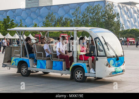 Voiture électrique auprès des touristes dans le contexte de l'Office national de natation dans le Parc olympique de Pékin Banque D'Images