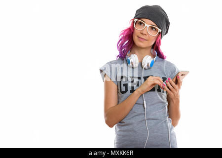 Studio shot of geek girl holding mobile phone en pensant wit Banque D'Images