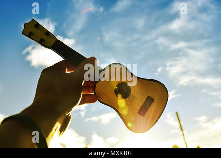 Les musiciens la tenue de la guitare dans le ciel au coucher du soleil. Concept de réussite Banque D'Images