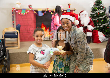 Airman Senior Denise Barnes, avec l'Air Force Reserve's 55e Escadron Port Aérien, pose pour une photo avec deux étudiants locaux au cours de l'Opération Père Noël à Togiak, 15 novembre 2016. Barnes a été l'un d'une poignée de réservistes du Travis Air Force Base, en Californie, qui participait à la formation annuelle conjointe à Base-Elmendorf Richardson et se sont portés volontaires pour participer à la Garde nationale de l'Alaska community outreach program. Maintenant dans sa 60e année, l'Opération Père Noël continue d'offrir des jouets, des fournitures scolaires et autres cadeaux aux enfants dans les villages de l'Alaska. (U.S. Photo de la Garde nationale Banque D'Images