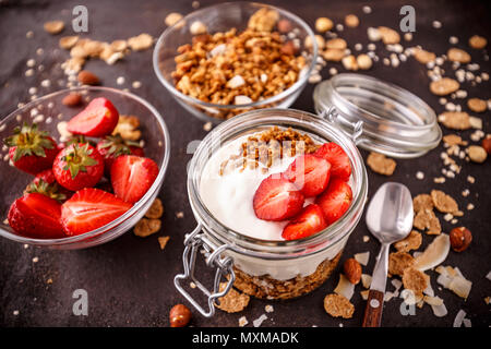Le yogourt avec granola maison cuites au four et des fraises dans un bocal en verre Banque D'Images